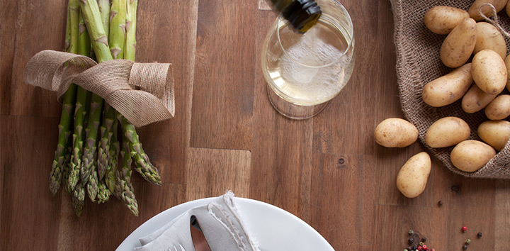 Grüner Spargel, Weißwein und Kartoffeln auf einem Tisch.