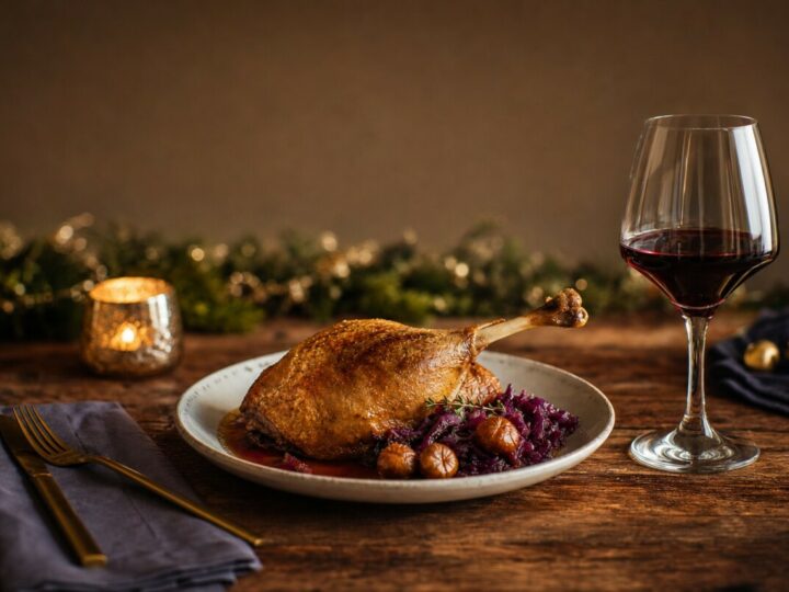 Gänsekeule mit Rotkohl und einem Glas Rotwein in weihnachtlichem Ambiente.