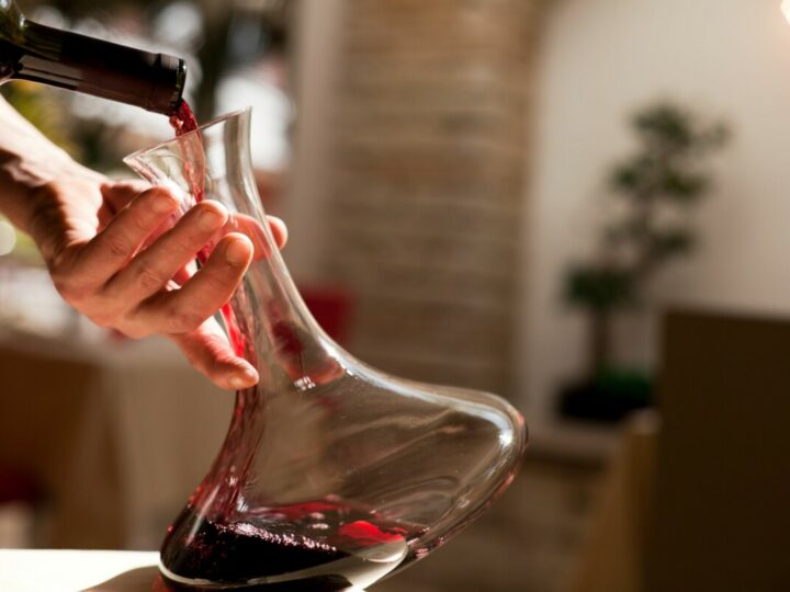 Ein Rotwein wird aus der Flasche dekantiert und in eine Karaffe gefüllt.