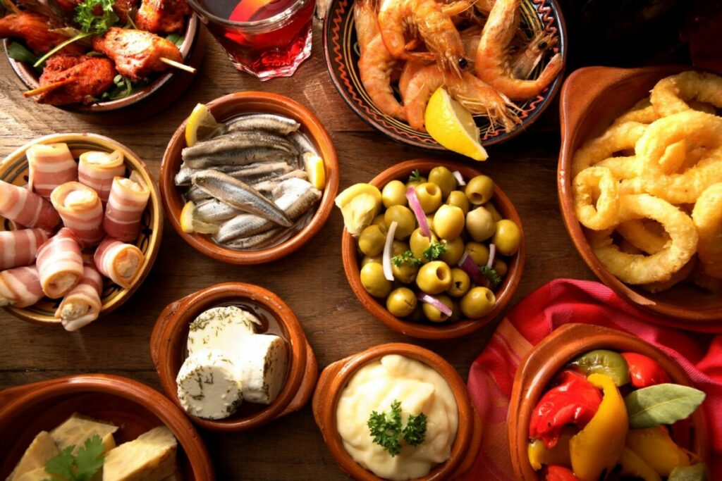 Diverse Tapas-Schälchen mit Sardellen, Oliven, Schinken, Käse und mehr.