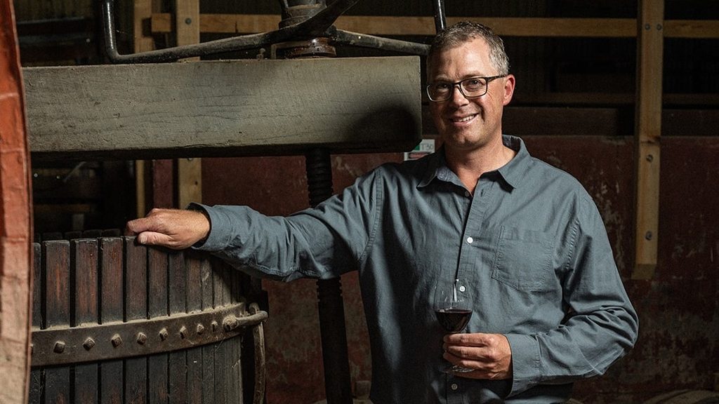Brett Schutz, Winemaker bei Peter Lehmann, im Weinkeller neben einem Fass Rotwein.
