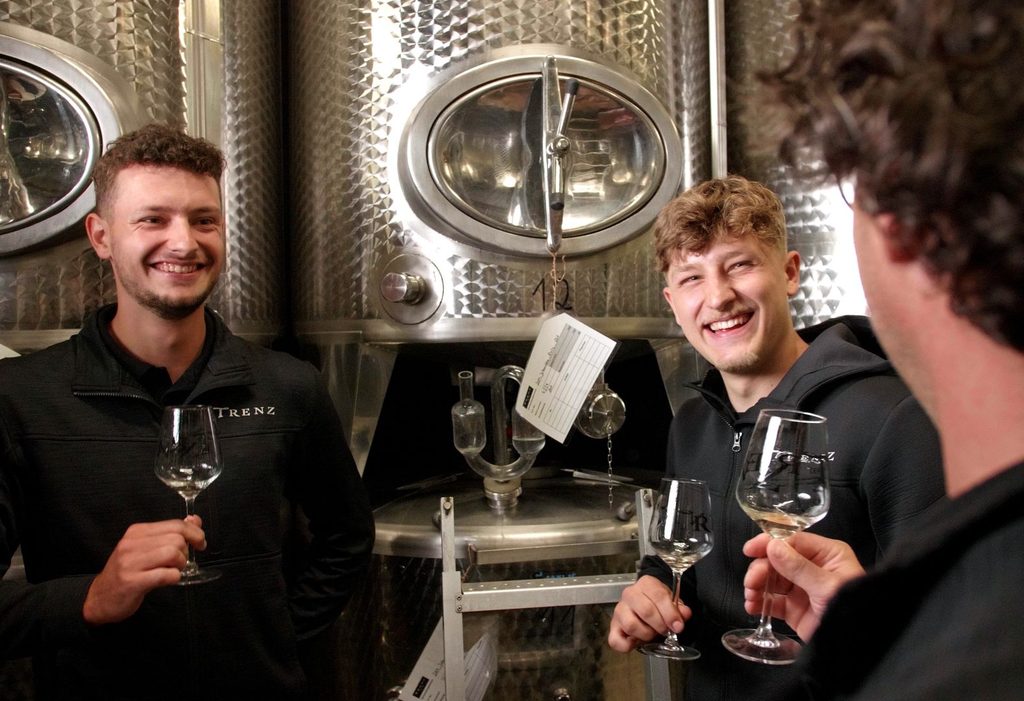 Drei Mitarbeiter des Weinguts Trenz verkosten Wein vor Edelstahltanks.